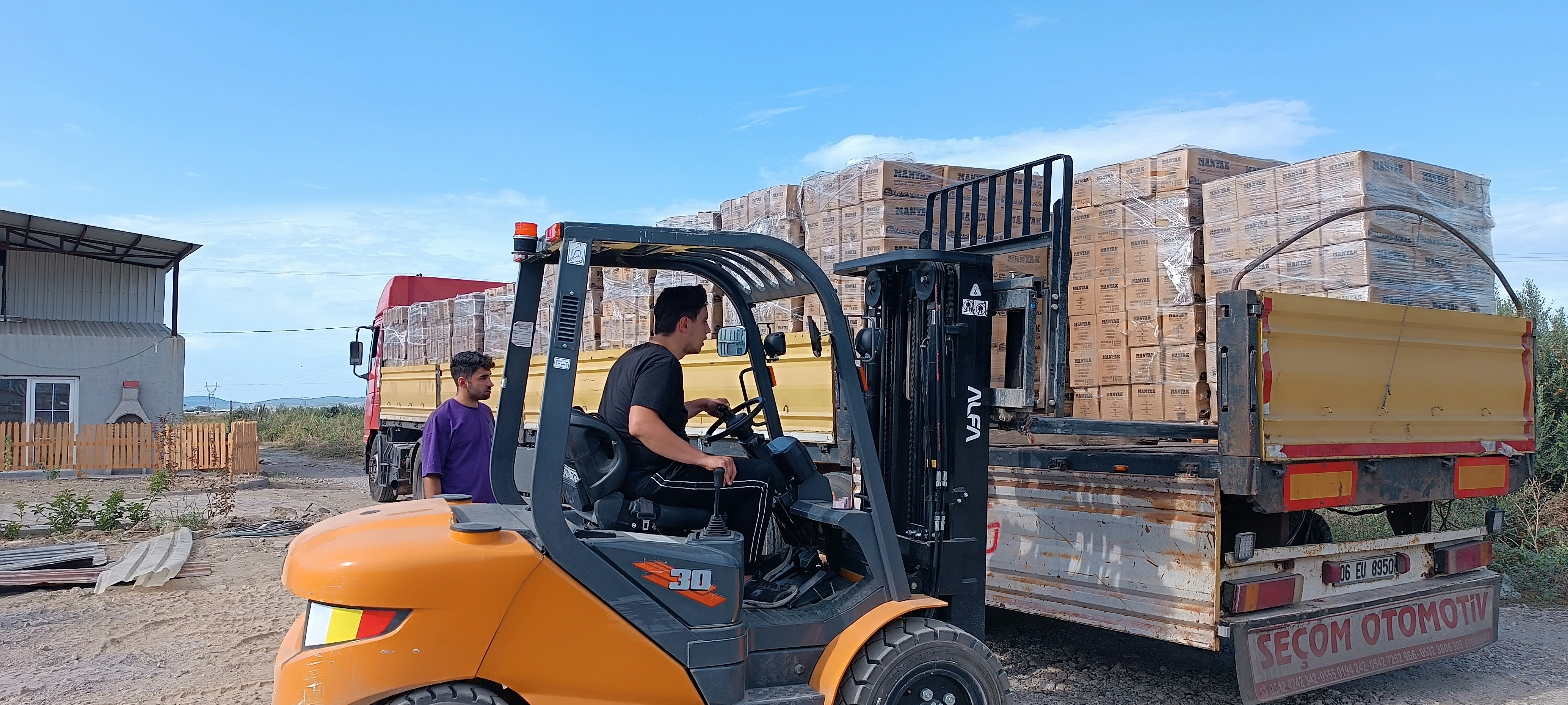 Forklift loading freight onto trucks at logistics facility